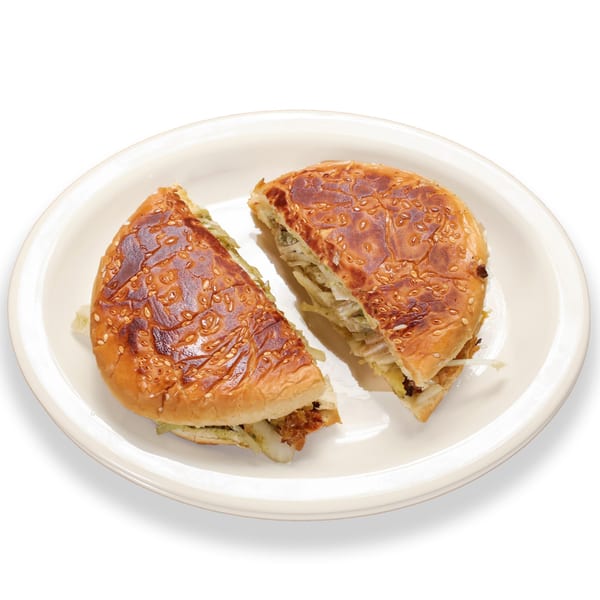 Two halves of a Pakistani bun kebab, filled with meat and onions, on a white plate.