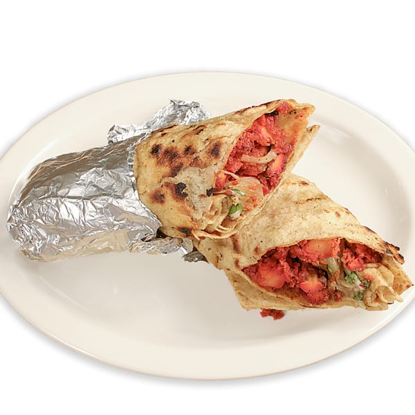 Two Pakistani chicken tikka rolls, one wrapped in foil, on a white plate.