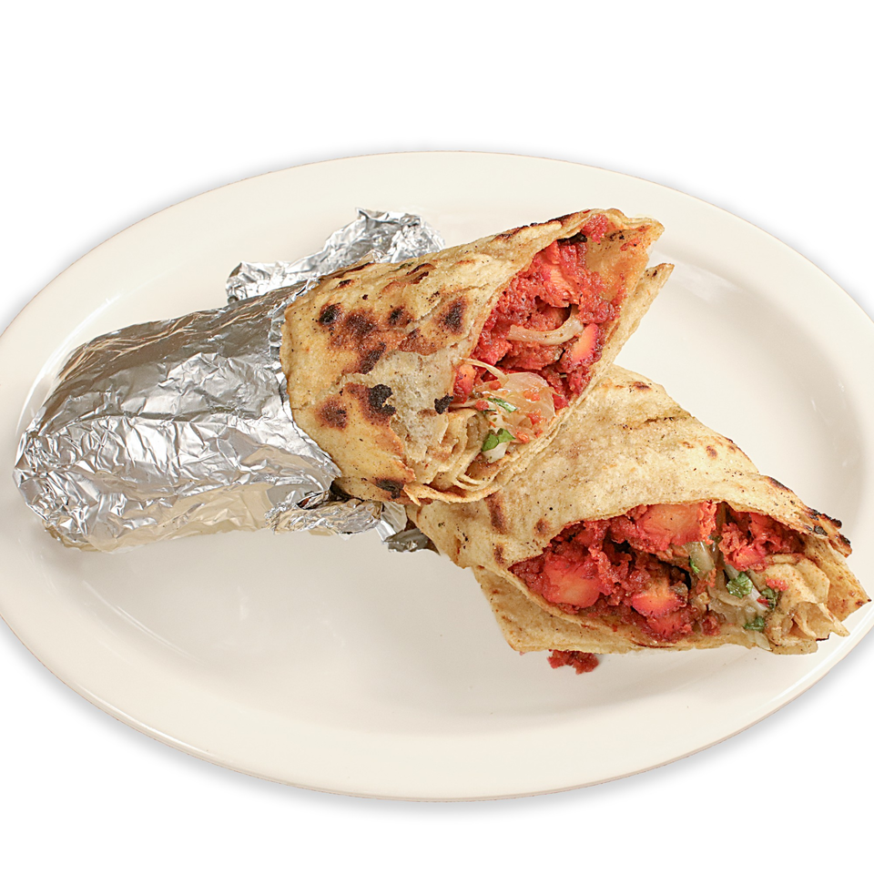 Two Pakistani chicken tikka rolls, one wrapped in foil, on a white plate.